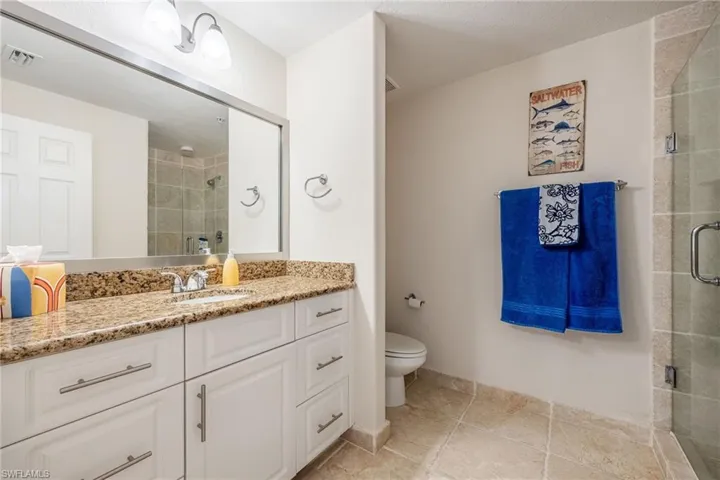 Bathroom featuring a shower with door, toilet, and vanity