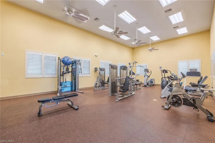 Exercise room with a towering ceiling and ceiling fan