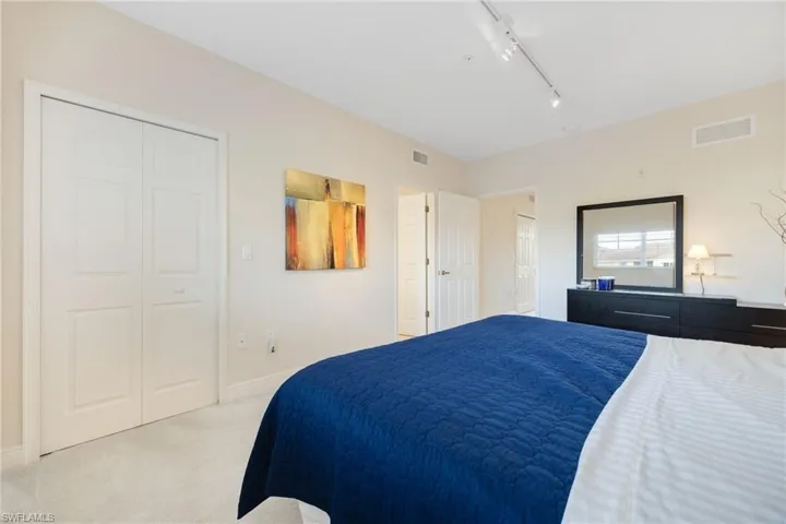 Carpeted upstairs bedroom with rail lighting and a closet