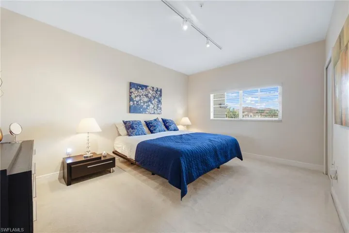Carpeted upstairs bedroom featuring rail lighting