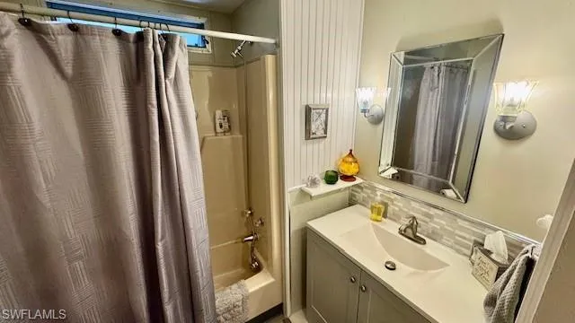 Bathroom with shower / tub combo with curtain, vanity, and decorative backsplash