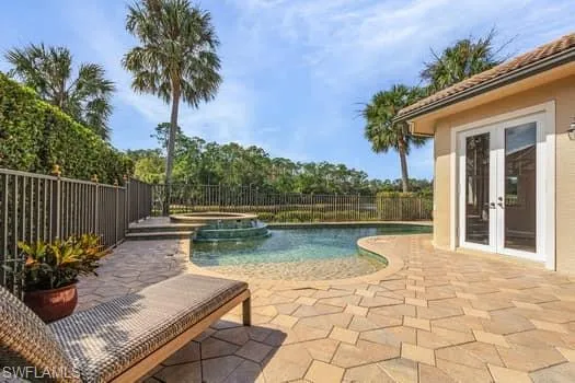 View of swimming pool with an in ground hot tub, a patio, and french doors