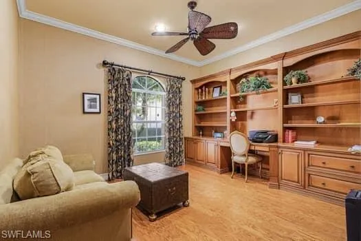 Office space featuring built in desk, ceiling fan, ornamental molding, and light hardwood / wood-style flooring