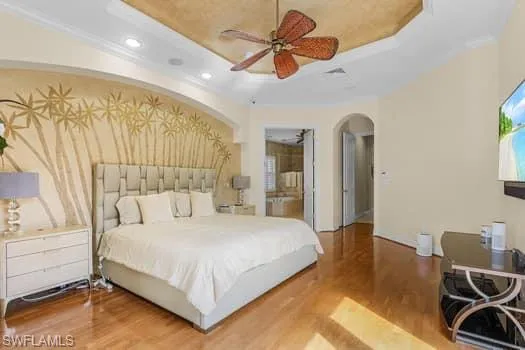 Bedroom featuring ceiling fan, hardwood / wood-style flooring, and a tray ceiling
