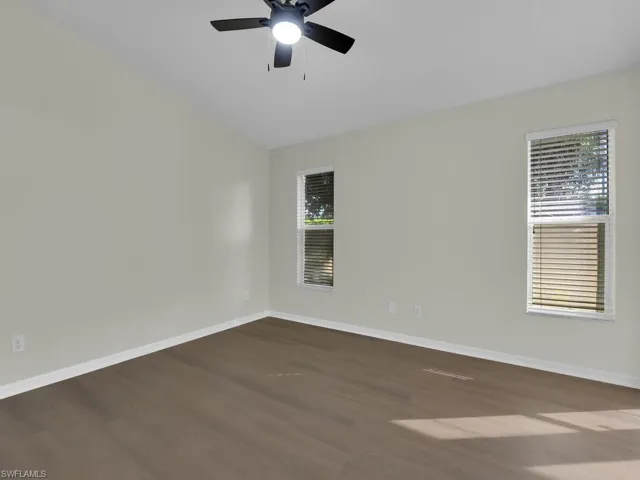 Spare room featuring plenty of natural light, ceiling fan, dark hardwood / wood-style flooring, and lofted ceiling