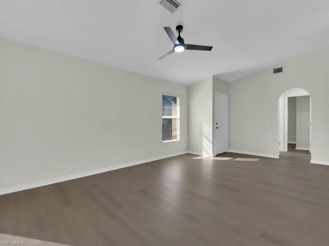 Empty room featuring dark wood-type flooring and ceiling fan