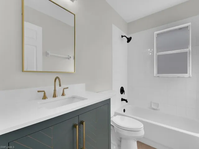 Full bathroom with tiled shower / bath, vanity, and toilet