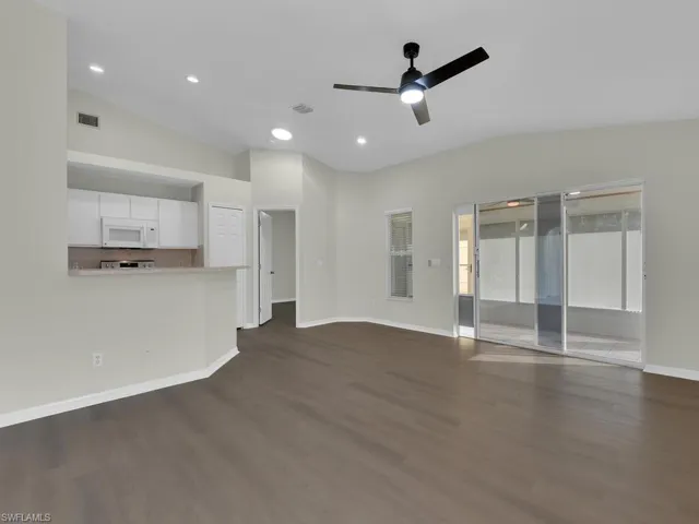 Unfurnished living room featuring ceiling fan, dark hardwood / wood-style flooring, and lofted ceiling