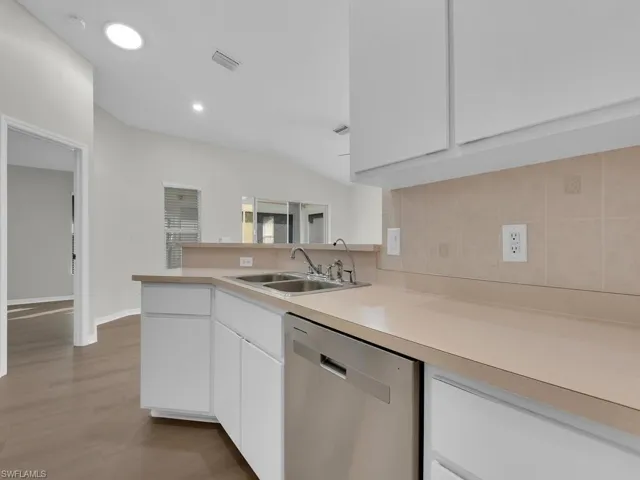 Kitchen with white cabinetry, hardwood / wood-style floors, sink, tasteful backsplash, and dishwasher