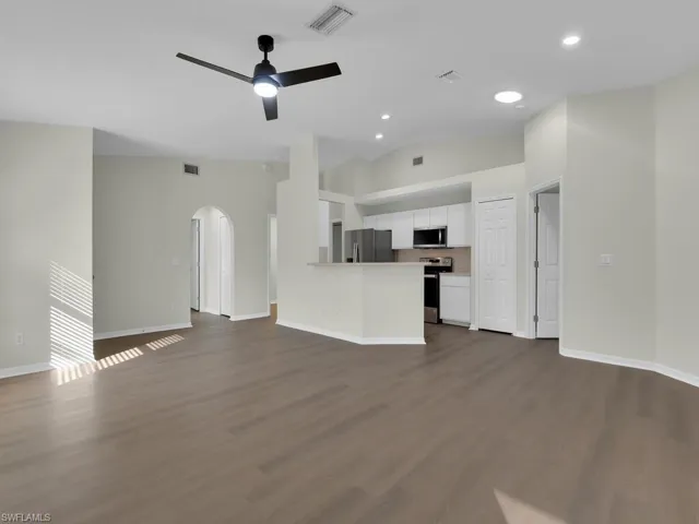 Unfurnished living room featuring high vaulted ceiling, dark hardwood / wood-style flooring, and ceiling fan
