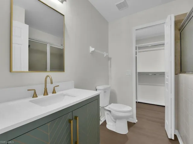 Bathroom with tile walls, large vanity, toilet, and hardwood / wood-style floors