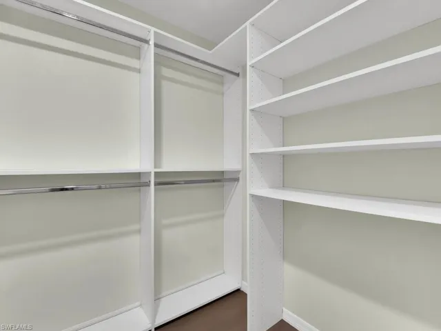 Spacious closet with dark hardwood / wood-style flooring