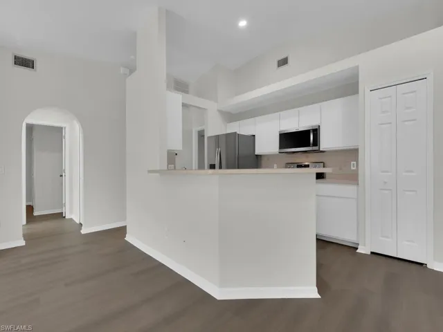 Kitchen featuring white cabinetry, dark hardwood / wood-style floors, tasteful backsplash, and stainless steel appliances