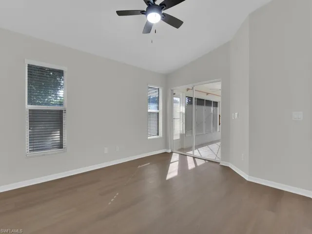 Empty room featuring ceiling fan, hardwood / wood-style flooring, and lofted ceiling