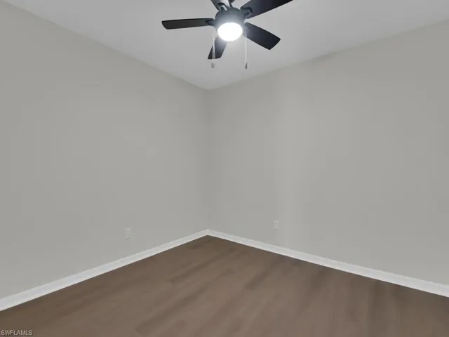 Spare room with ceiling fan and dark wood-type flooring