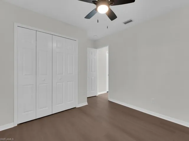 Unfurnished bedroom featuring a closet, ceiling fan, and dark hardwood / wood-style flooring