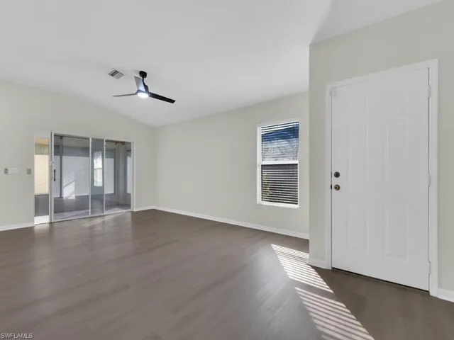 Empty room with vaulted ceiling, dark hardwood / wood-style flooring, and ceiling fan