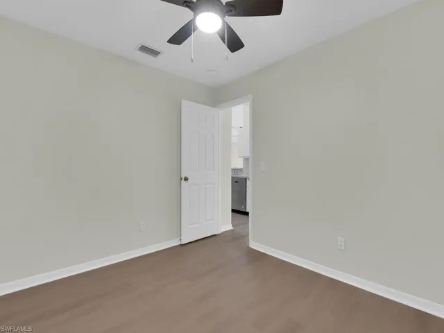 Empty room featuring ceiling fan and dark hardwood / wood-style flooring
