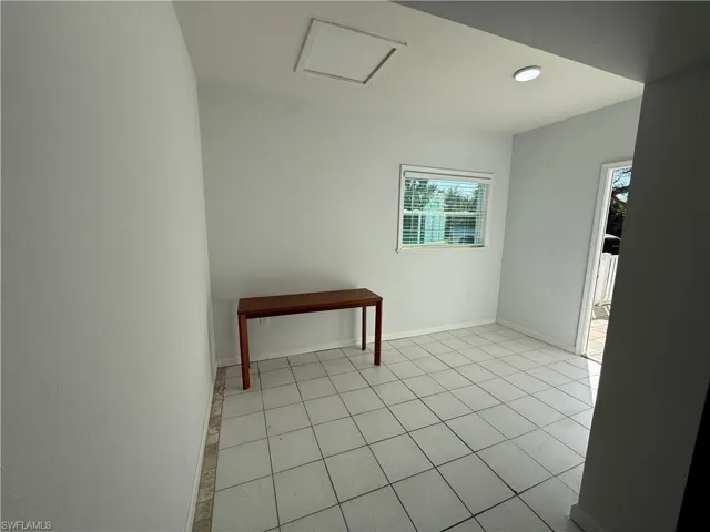 Empty room with attic access and light tile patterned floors