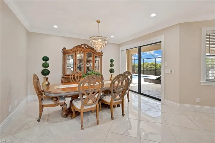 Dining space featuring ornamental molding, light tile flooring, and a chandelier