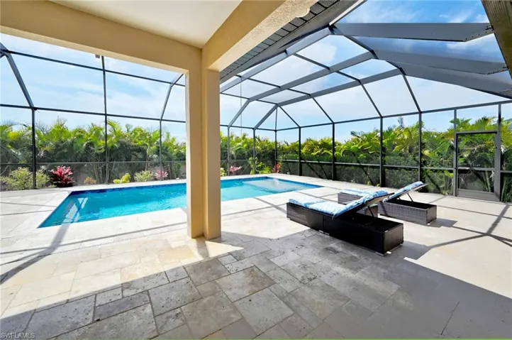View of pool featuring glass enclosure and a patio area