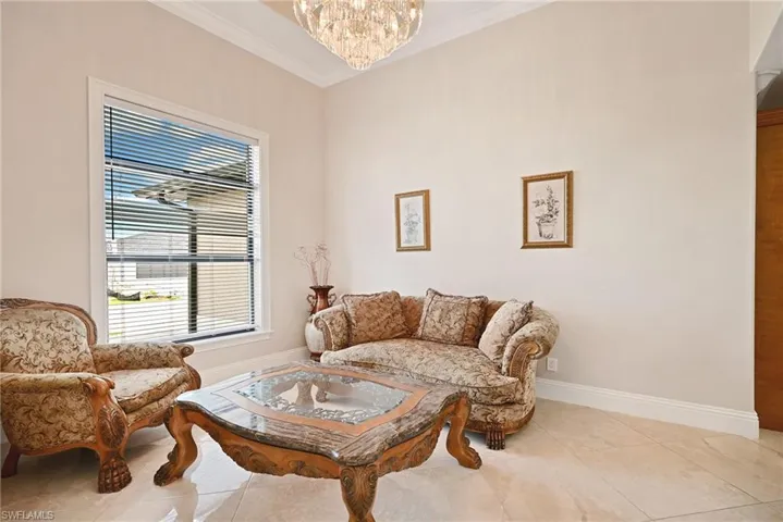 Tiled living room with ornamental molding and an inviting chandelier