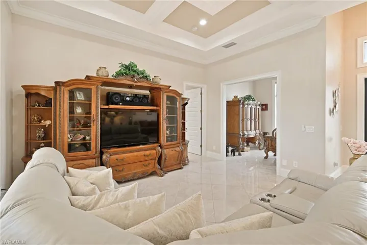 Tiled living room with a high ceiling, coffered ceiling, and ornamental molding