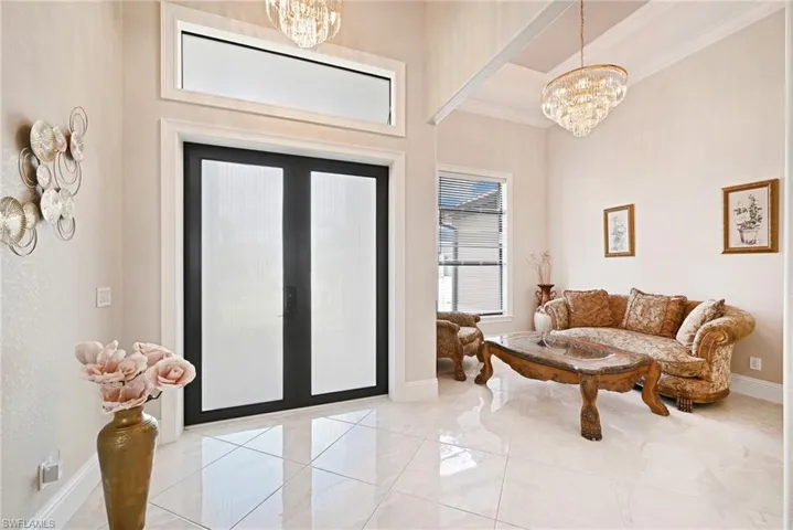 Entryway with a notable chandelier, a towering ceiling, ornamental molding, and french doors