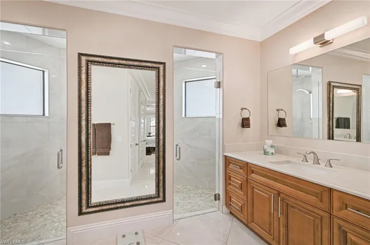 Bathroom featuring a shower with door, tile flooring, ornamental molding, and oversized vanity