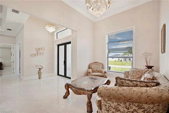 Sitting room featuring an inviting chandelier, light tile flooring, french doors, and crown molding
