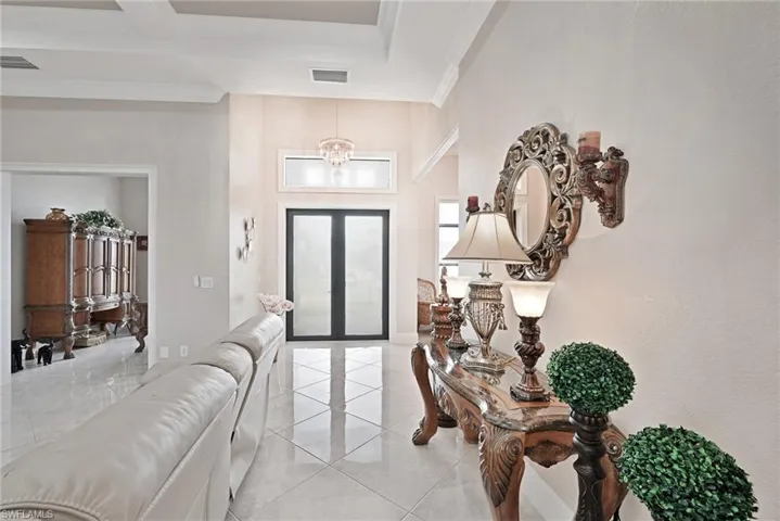 Foyer entrance with ornamental molding, a chandelier, and light tile floors