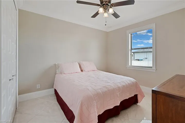 Tiled bedroom featuring ornamental molding and ceiling fan