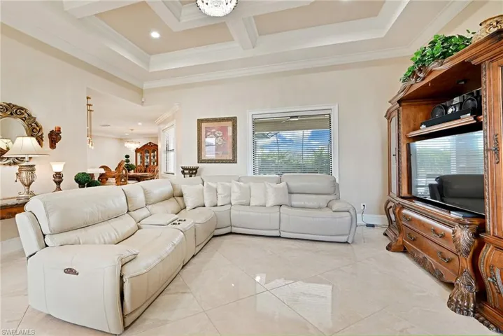 Tiled living room with coffered ceiling, beam ceiling, and crown molding