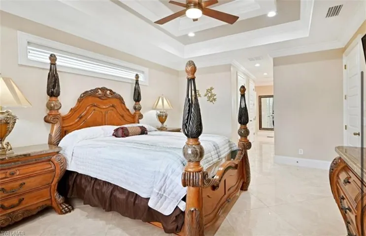Bedroom featuring ceiling fan, a closet, crown molding, a raised ceiling, and light tile floors