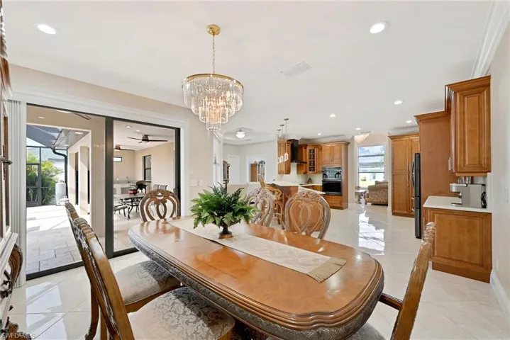Tiled dining area featuring ceiling fan with notable chandelier, crown molding, and a wealth of natural light