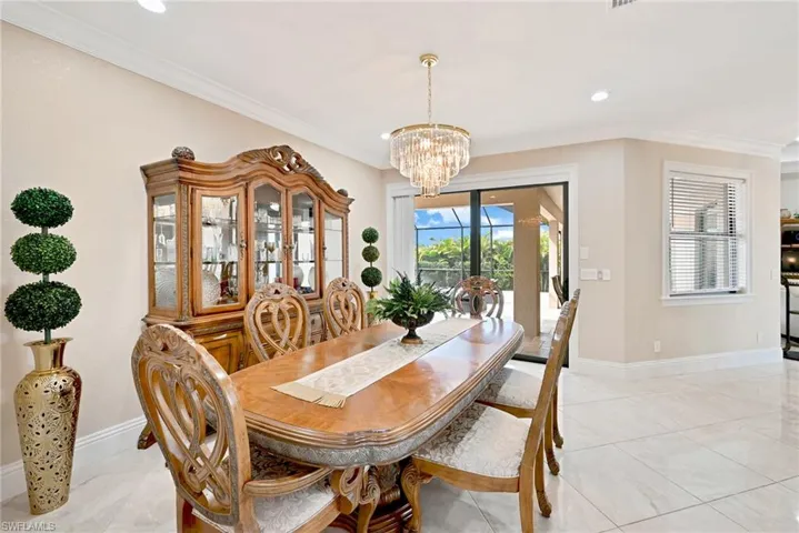 Dining room with crown molding, a chandelier, and light tile floors