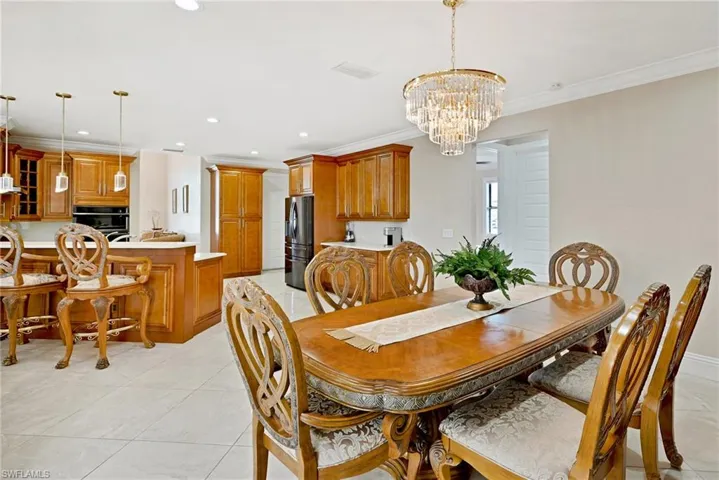 Dining area featuring a chandelier, light tile flooring, and crown molding