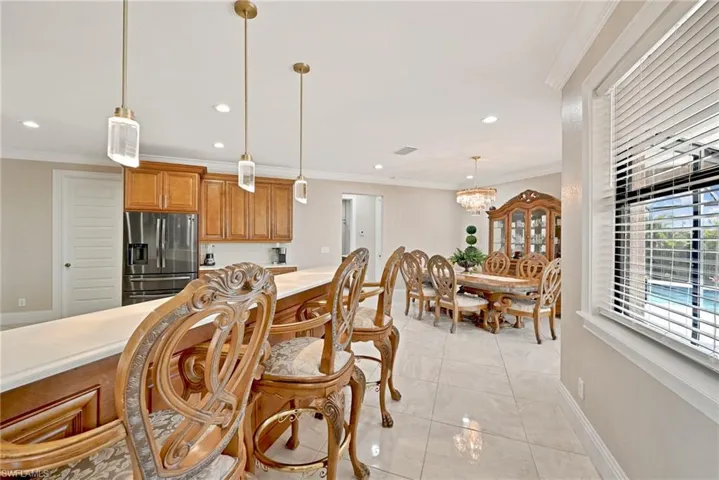Kitchen with stainless steel fridge, an inviting chandelier, light tile floors, hanging light fixtures, and ornamental molding
