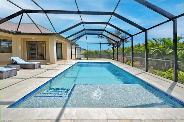 View of pool featuring a patio, glass enclosure, and pool water feature