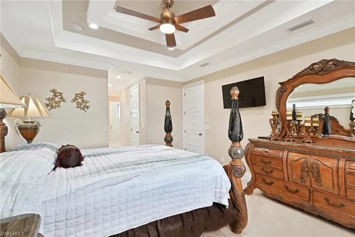 Bedroom with ornamental molding, ceiling fan, and a raised ceiling