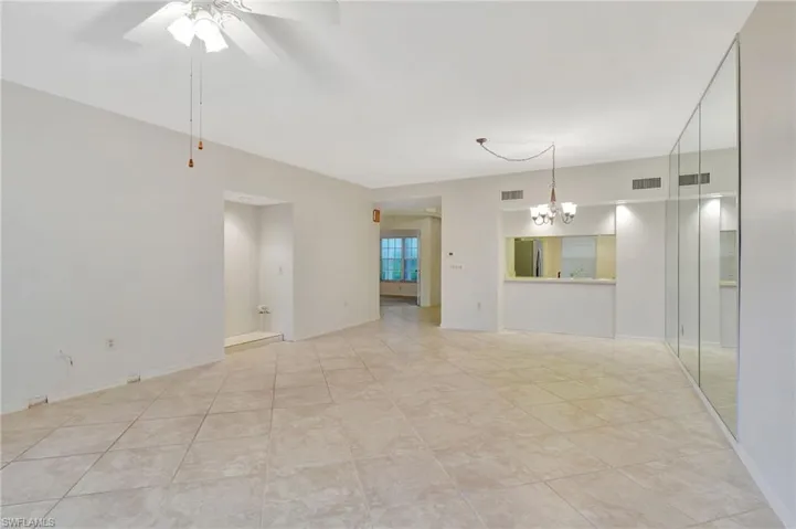 Spare room with light tile patterned flooring and ceiling fan with notable chandelier