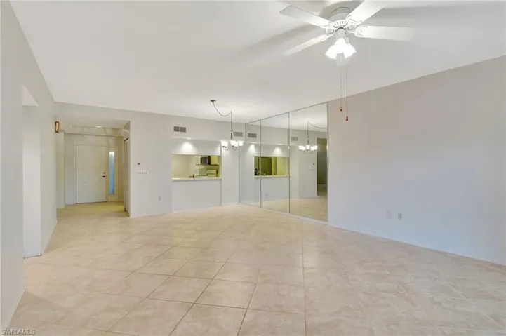 Spare room featuring light tile patterned flooring and ceiling fan with notable chandelier