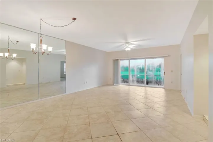 Tiled empty room with ceiling fan with notable chandelier
