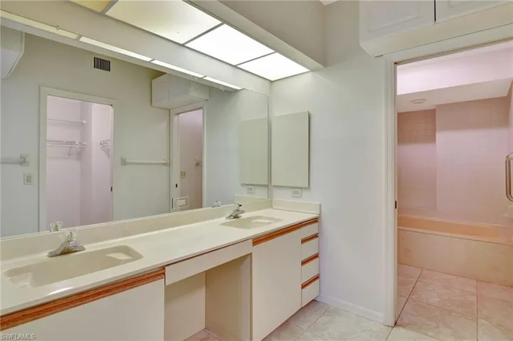 Bathroom with double vanity, tile patterned floors, and shower / bathtub combination