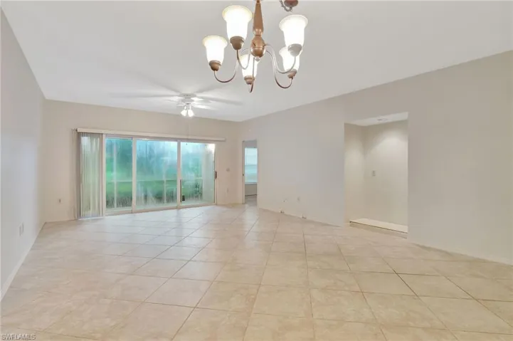 Unfurnished room with light tile patterned flooring and ceiling fan with notable chandelier