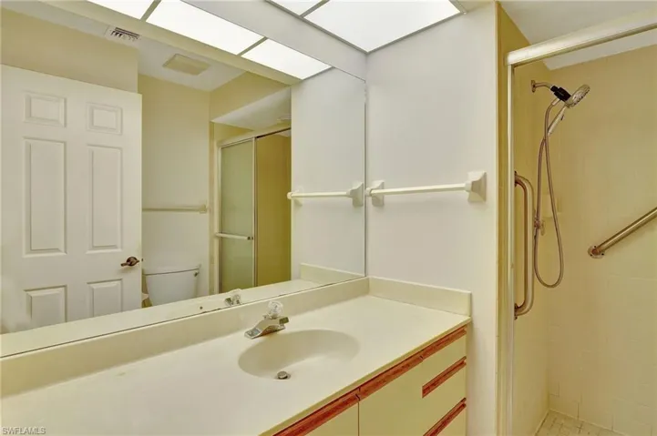Bathroom with a shower with door, vanity, and toilet