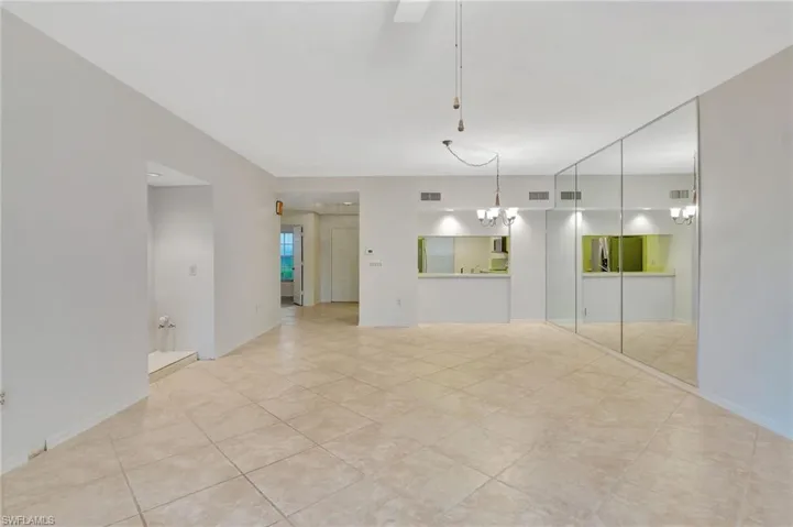 Tiled spare room featuring an inviting chandelier