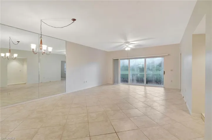 Tiled spare room with ceiling fan with notable chandelier