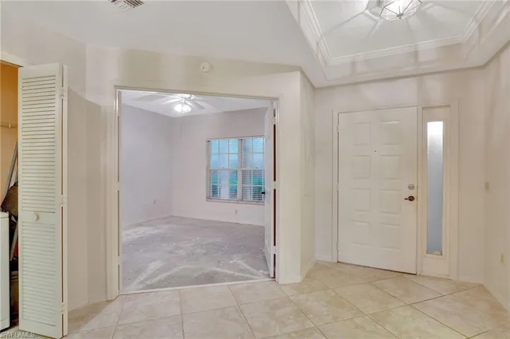 Entryway with ornamental molding, light tile patterned floors, and ceiling fan