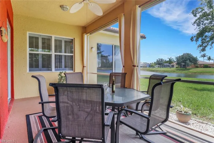 Sunroom / solarium featuring a textured wall, outdoor dining area, a water view, ceiling fan, and carpet